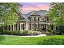 Charming two-story brick home featuring manicured lawn, black shutters, and inviting front entrance at 3306 Delamere Dr, Matthews, NC 28104