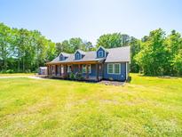 Charming blue home with a covered porch and mature trees, set on a sunny lot with green grass at 3546 Mount Pleasant N Rd, Concord, NC 28025