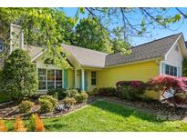 Charming yellow home with lush landscaping, including flowering shrubs, mature trees, and a well-manicured lawn at 6307 Old Corral St, Charlotte, NC 28277