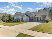 Charming single-story home with a two-car garage, stone accents, manicured lawn and covered front porch with rocking chairs at 8011 Green Heron Ct, Belmont, NC 28012