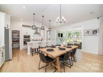 Bright, open kitchen/dining area with large island, pendant lights, and seamless flow to outdoor living space at 8011 Green Heron Ct, Belmont, NC 28012