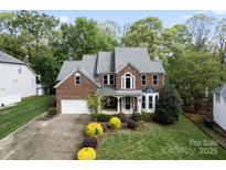 Beautiful two-story brick home with a well-manicured lawn, mature trees, and attached two car garage at 9009 Tayside Ct, Huntersville, NC 28078