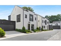 Charming modern-style townhome with black frame windows, light brick, manicured landscaping, and a black two-car garage at 9020 Tynecastle Commons Ct, Charlotte, NC 28226