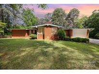 Charming single-story brick home featuring a well-manicured lawn and mature trees at 1012 Hawkinstown Rd, Salisbury, NC 28144
