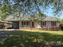 Charming single-story home featuring a well-manicured lawn, front porch, and convenient carport at 107 Plumtree Dr, Kings Mountain, NC 28086