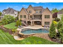 Stunning backyard features a luxurious pool, stone patio, lush landscaping, and a spacious screened porch at 17909 Golden Meadow Ct, Davidson, NC 28036