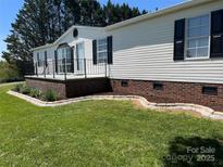 Inviting exterior features white siding, black shutters, brick foundation, and a charming front porch with black railing at 186 Ellendale Ln, Taylorsville, NC 28681