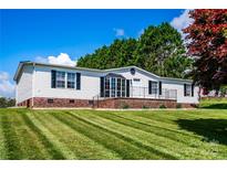Charming single-story home featuring tidy landscaping, brick foundation and neutral siding and black shutters at 186 Ellendale Ln, Taylorsville, NC 28681