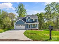 Charming two-story home with blue siding, an attached two-car garage and a well-manicured lawn at 2668 Polo Ln, Maiden, NC 28650