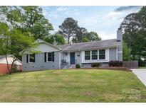 Charming gray brick home with a well-manicured front yard and a pop of color on the front door at 6701 Highbrook Dr, Charlotte, NC 28212