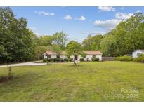 Sprawling front yard with mature trees and a well-maintained lawn leads up to a charming ranch-style home at 7200 Monroe Rd, Charlotte, NC 28212