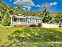 Charming single-story home featuring a welcoming front porch and well-maintained lawn on a sunny day at 9007 Mcmillian Dr, Harrisburg, NC 28075