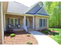 Charming brick home featuring a cozy front porch with seating and a beautifully landscaped yard at 107 Garden Ter, Dallas, NC 28034