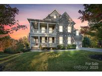 Stunning two-story home features a stone facade, inviting double porches, and professional landscaping at 14010 Promenade Dr, Huntersville, NC 28078