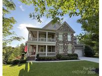 Charming two-story home featuring a stone facade, double porches, lush lawn, and attached garage at 14010 Promenade Dr, Huntersville, NC 28078