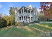 Charming two-story home boasting a double porch, stone accents, and a well-manicured lawn at 14010 Promenade Dr, Huntersville, NC 28078