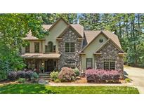 Beautiful two-story home with a stone facade, manicured lawn, and lush landscaping at 14130 Lea Point Ct, Huntersville, NC 28078