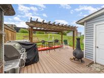 Outdoor deck featuring grill, pergola, chiminea, and table set with a scenic view of a grassy lawn at 1424 River Dr, Belmont, NC 28012