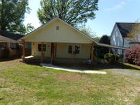 Quaint exterior of a light yellow house with a covered porch and ample green lawn at 202 S Love Chapel Rd, Stanfield, NC 28163