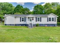 Charming single-story home featuring a well-maintained lawn, dark shutters, and a welcoming front entrance at 220 Tomberlin Rd, Mount Holly, NC 28120