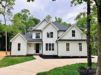 Stunning two-story home with white siding, black accents, a well manicured lawn, and a concrete driveway at 3308 Watkins Rd, Monroe, NC 28110
