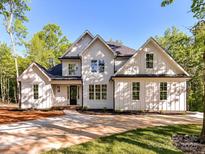 Stunning two-story home boasts a modern farmhouse design, complemented by lush landscaping and a concrete driveway at 3308 Watkins Rd, Monroe, NC 28110