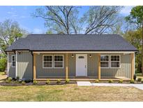 Inviting home featuring a covered porch with wood columns, green siding and a modern white front door at 6525 Kershaw Camden Hwy, Heath Springs, SC 29058