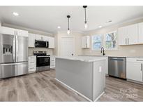 Modern kitchen featuring stainless steel appliances, white cabinets, and a center island with a light gray finish at 6525 Kershaw Camden Hwy, Heath Springs, SC 29058
