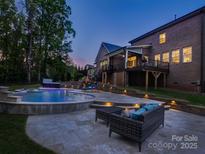 Inviting backyard featuring a pool, spa, stone patio, and covered deck, perfect for outdoor entertaining at 712 Chase Ct, Fort Mill, SC 29708
