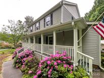 Charming two-story home featuring a spacious front porch adorned with beautiful pink flowers and an American flag at 2214 Cannonade Ct, Matthews, NC 28105
