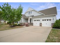 Charming home featuring a two-car garage, stone accents, manicured landscaping, and a welcoming front porch at 13115 Union Square Dr, Huntersville, NC 28078