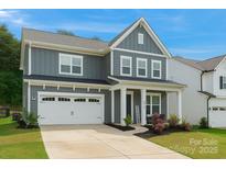 Charming two-story home with grey siding, white trim, attached garage, and manicured landscaping at 1390 Cedardale Ln, Denver, NC 28037