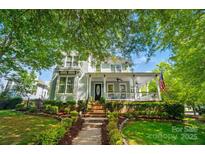 Inviting two-story home with a charming front porch, lush landscaping, and mature trees at 648 Revival Row, Fort Mill, SC 29708
