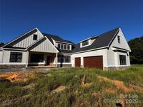 Stunning new construction features light colored vertical siding, dark trim, and a two car garage at 6511 Rehobeth Rd, Waxhaw, NC 28173