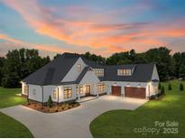 Stunning exterior of a modern farmhouse with a three-car garage and long driveway at 6511 Rehobeth Rd, Waxhaw, NC 28173