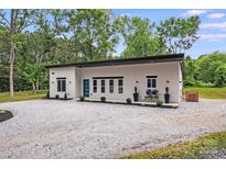 Modern single story home with a gravel driveway and minimalist landscaping at 6907 Lancaster Hwy, Waxhaw, NC 28173