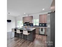 Modern kitchen boasts stainless appliances, gray wood cabinets, an island with seating, and lots of natural light at 6907 Lancaster Hwy, Waxhaw, NC 28173