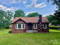 Charming brick home with a well-manicured lawn, flower beds, and a classic brick chimney at 717 Wilshire Sw Ave, Concord, NC 28025