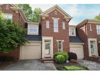 Charming brick townhome featuring a well-maintained front yard, attached garage, and welcoming entrance at 879 Park Slope Dr, Charlotte, NC 28209