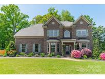 Charming two-story brick home featuring lush landscaping and a well-manicured lawn at 12525 Hashanli Pl, Matthews, NC 28105