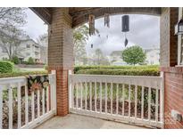 Cozy, covered patio with brick columns, white railing, and views of the community lawn at 16746 Amberside E Rd, Cornelius, NC 28031