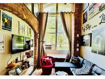 Inviting living room featuring exposed brick, large window, and stylish decor at 201 S Hoskins Rd # 132, Charlotte, NC 28208