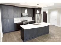Modern kitchen featuring stainless steel appliances, island with white countertops and dark wood cabinets at 222 S Caldwell St # 1801, Charlotte, NC 28202