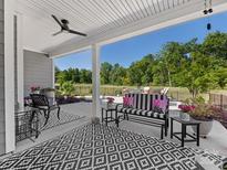 Inviting outdoor patio featuring a black and white patterned rug, stylish furniture, and scenic backyard view at 4012 Moxie Way, Charlotte, NC 28215