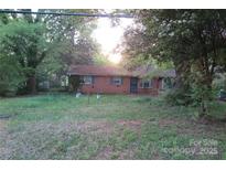 A single-story brick home with a large front yard and mature trees, capturing its curb appeal at 4814 Chapel Grove Rd, Gastonia, NC 28052
