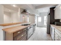 Modern kitchen with wood counters, stainless steel appliances, and updated gray wood-look floors at 5901 Quail Hollow Rd # G, Charlotte, NC 28210