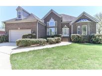 Charming brick home features a manicured lawn, lush bushes, and an attached two-car garage at 115 Players Park Cir, Statesville, NC 28677