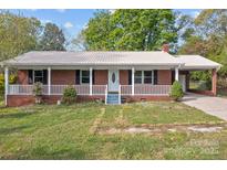 Charming brick home featuring a covered porch, metal roof, and well-maintained landscaping at 1195 Ralph B Keener Rd, Lincolnton, NC 28092