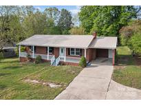 Charming brick home featuring a well-maintained yard, a metal roof, and an attached carport at 1195 Ralph B Keener Rd, Lincolnton, NC 28092