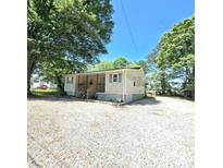 Inviting one-story home with a covered porch and gravel driveway, nestled among mature trees at 1307 Washington Ln, Kannapolis, NC 28083